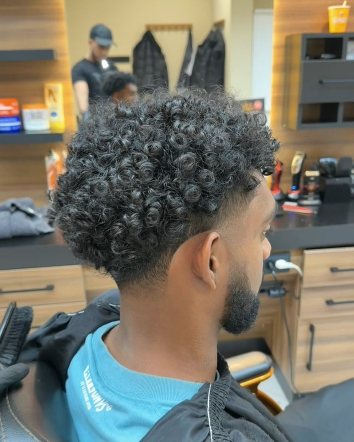 Curly fade met natuurlijke textuur bij RochBarber